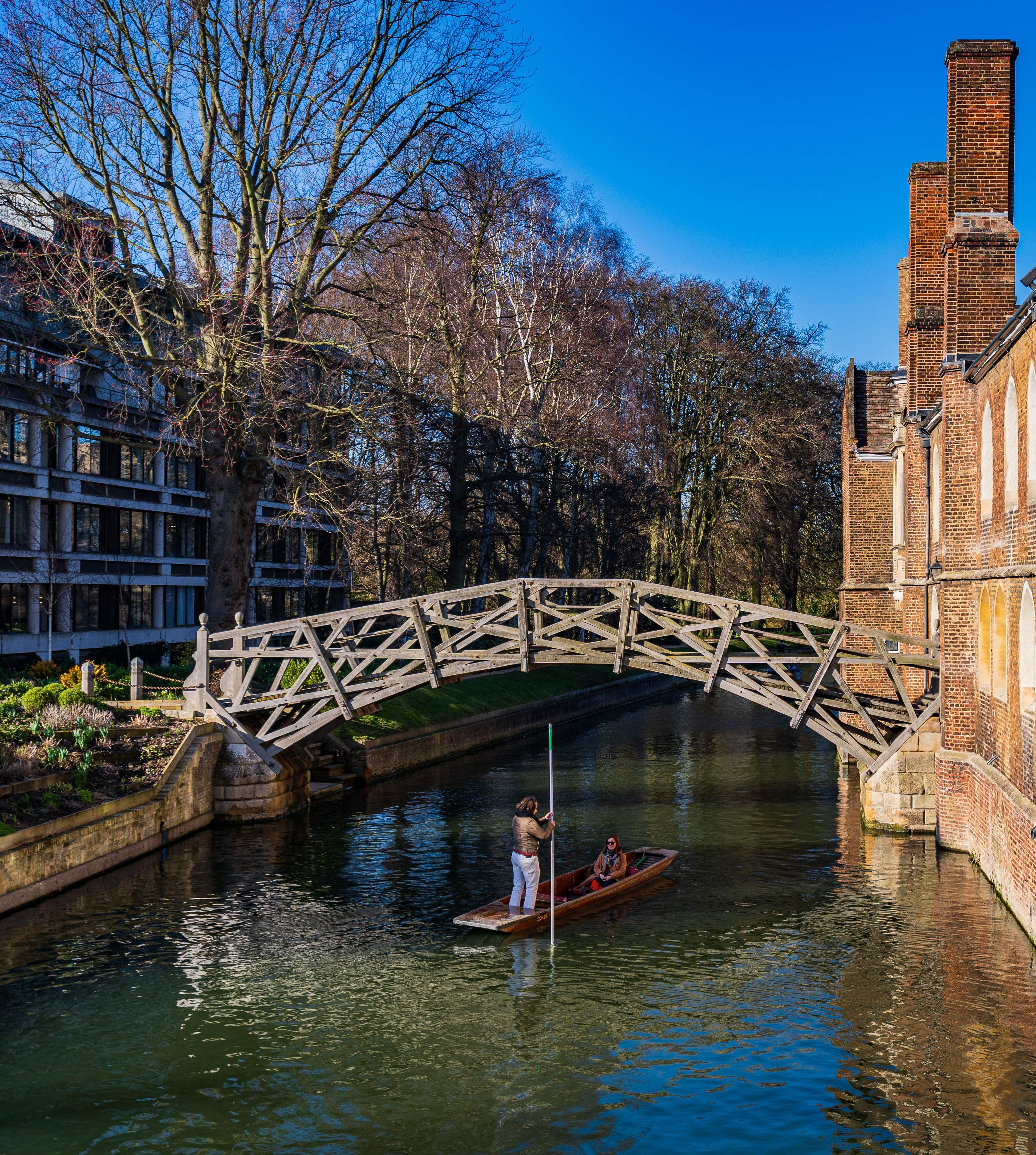 A couple punting on river Cam under famous Mathematical Bridge, Cambridge UK