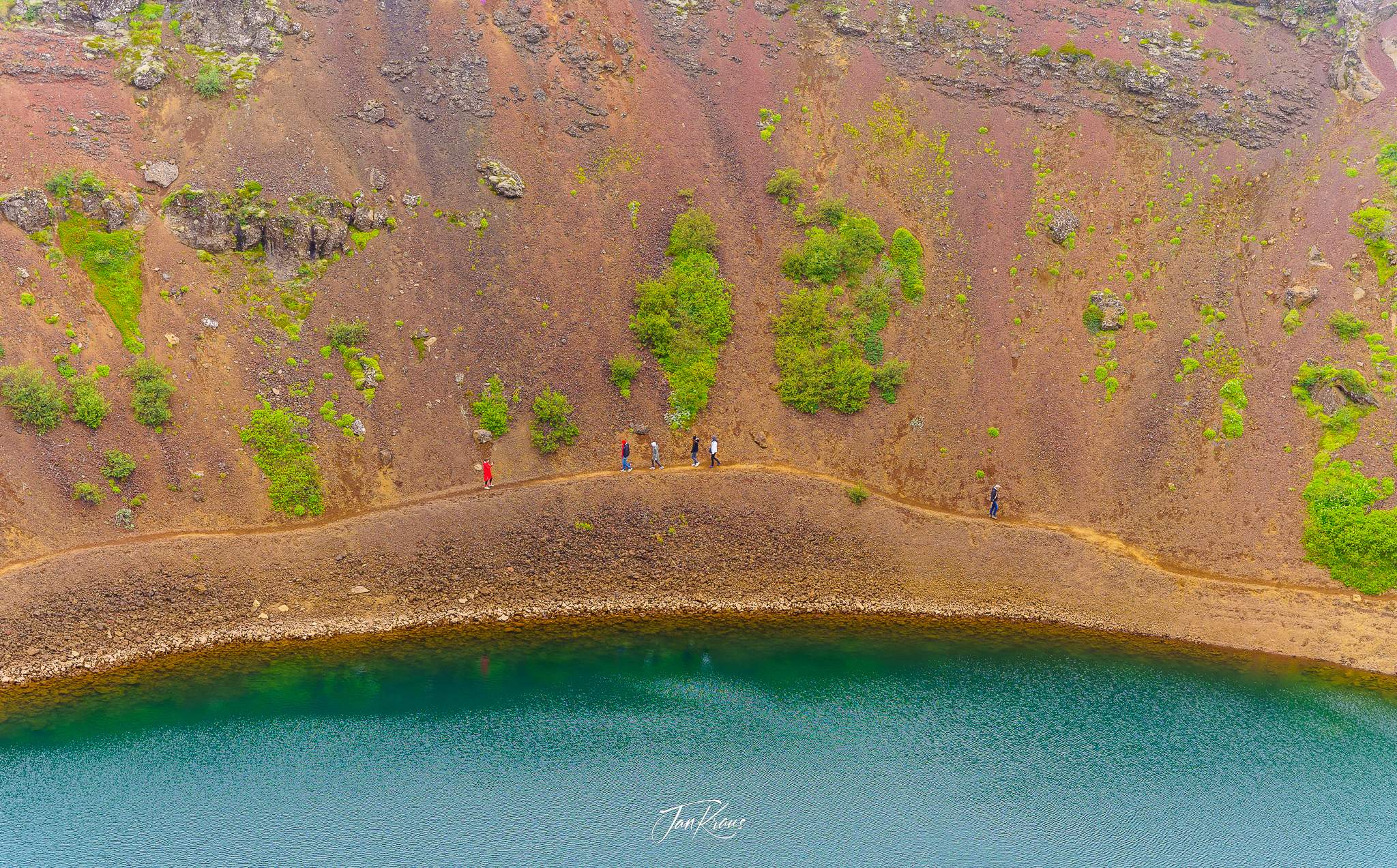 People walking narrow path at the edge of the lake inside Kerid Crater, Iceland