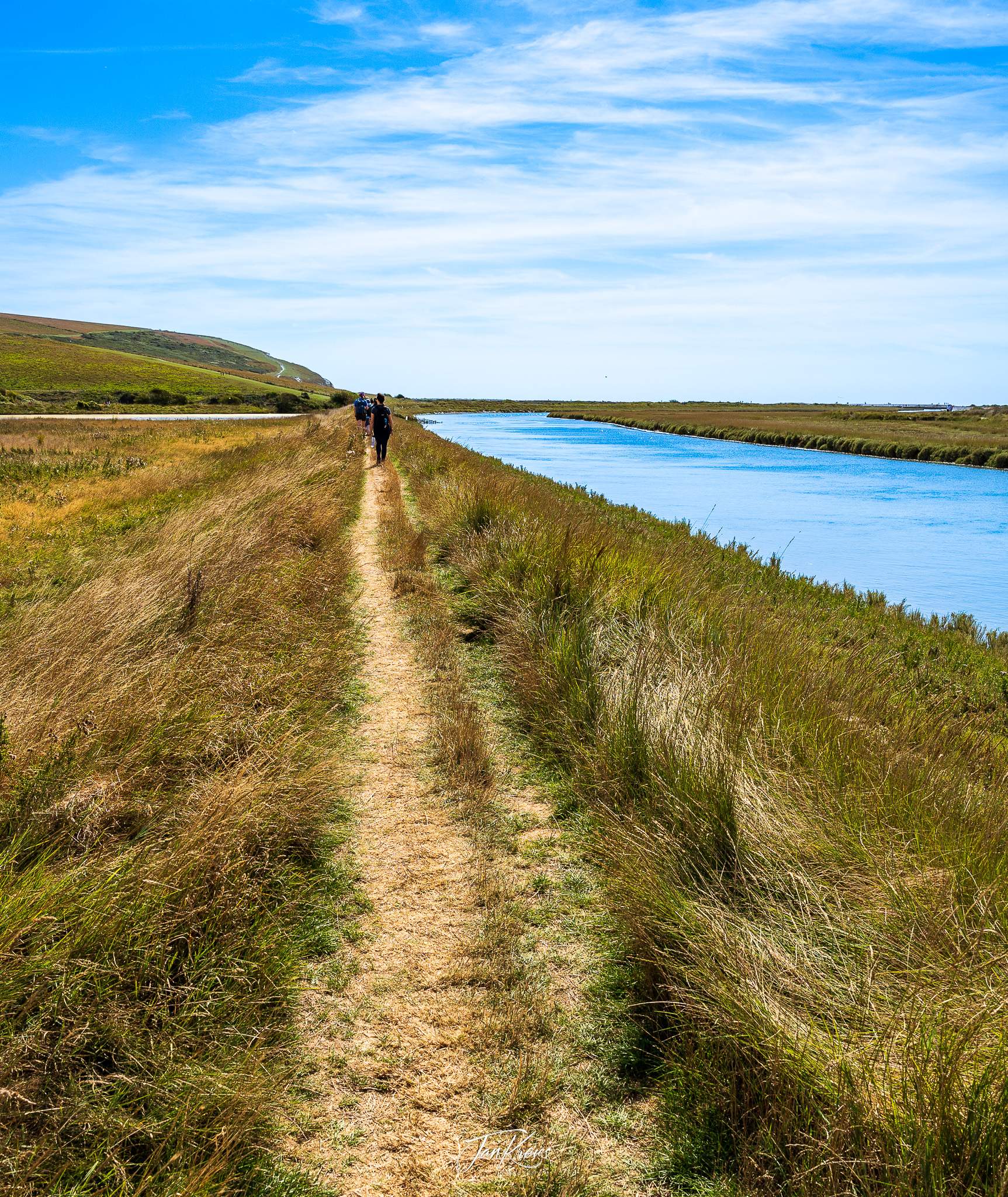 A path leading along the Cuckmere River at the Seven Sisters Walk, East Sussex, England, UK