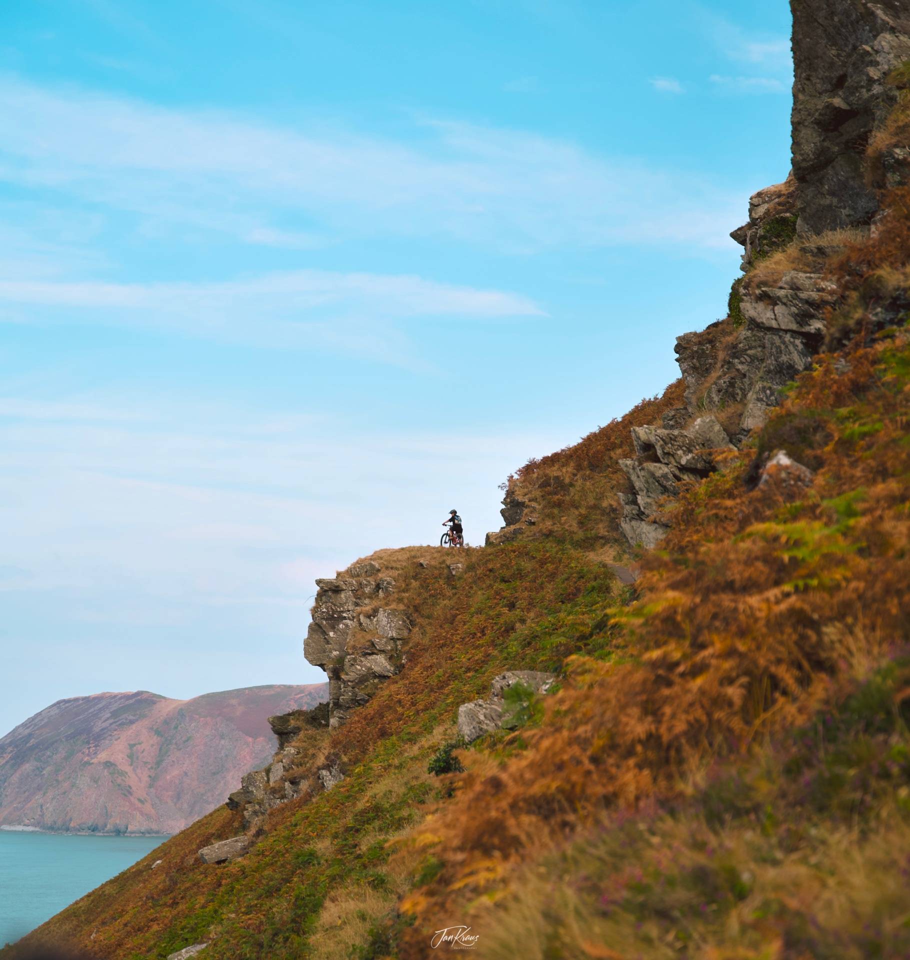 A biker on the path at the edge of the cliffs in the Valley of the Rocks, Exmoor National Park, UK